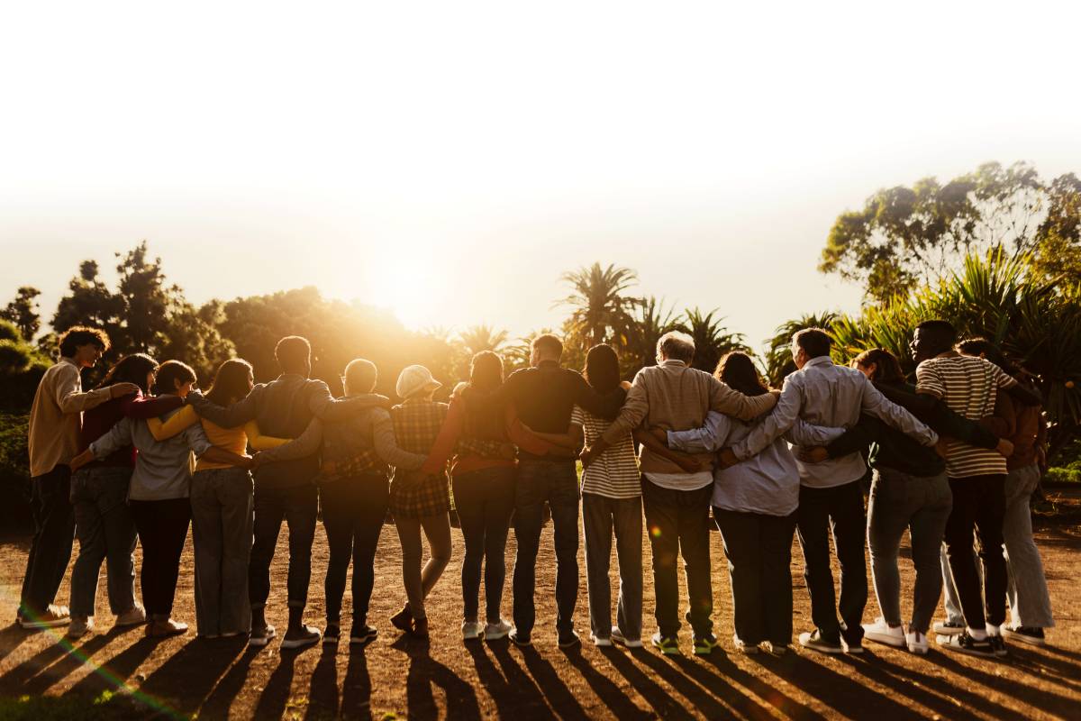 Group of people standing in a line with their arms around each other.